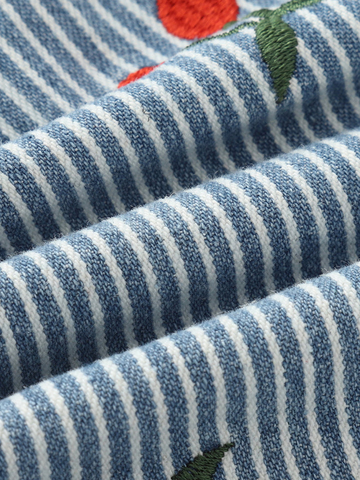 Macro view of the blue and white stripe cotton weave and cherry embroidery on Girls’ shorts