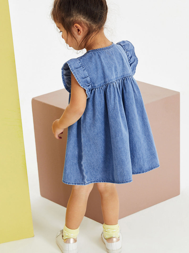 Close-up of colorful cloud, sunshine, tulip and dinosaur appliqués on a girls blue jean dress
