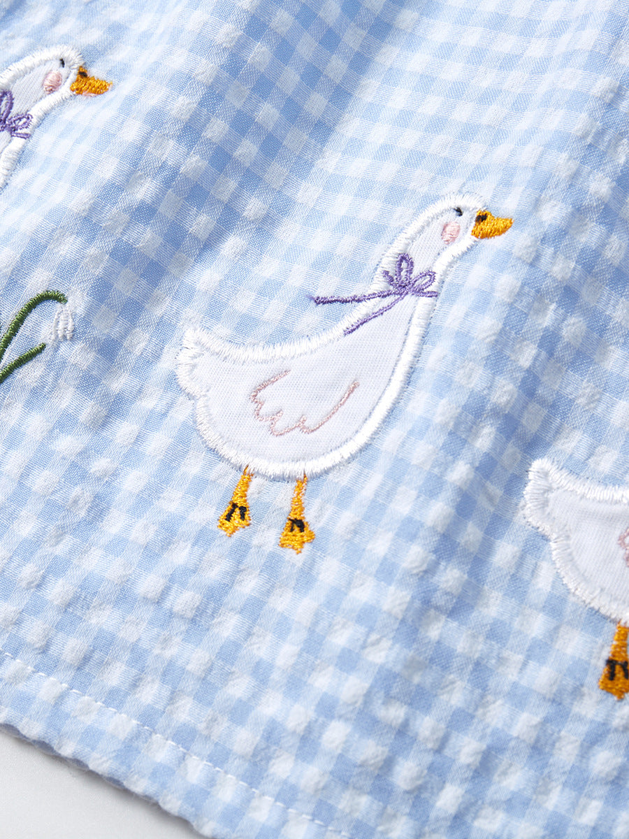 Close-up of white goose embroidery on sky blue gingham girls sleeveless dress