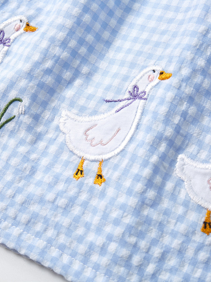 Close-up of white goose embroidery on sky blue gingham girls sleeveless dress